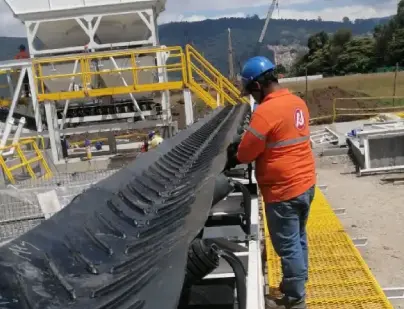 Trabajador en una obra revisando las poleas de una banda transportadora